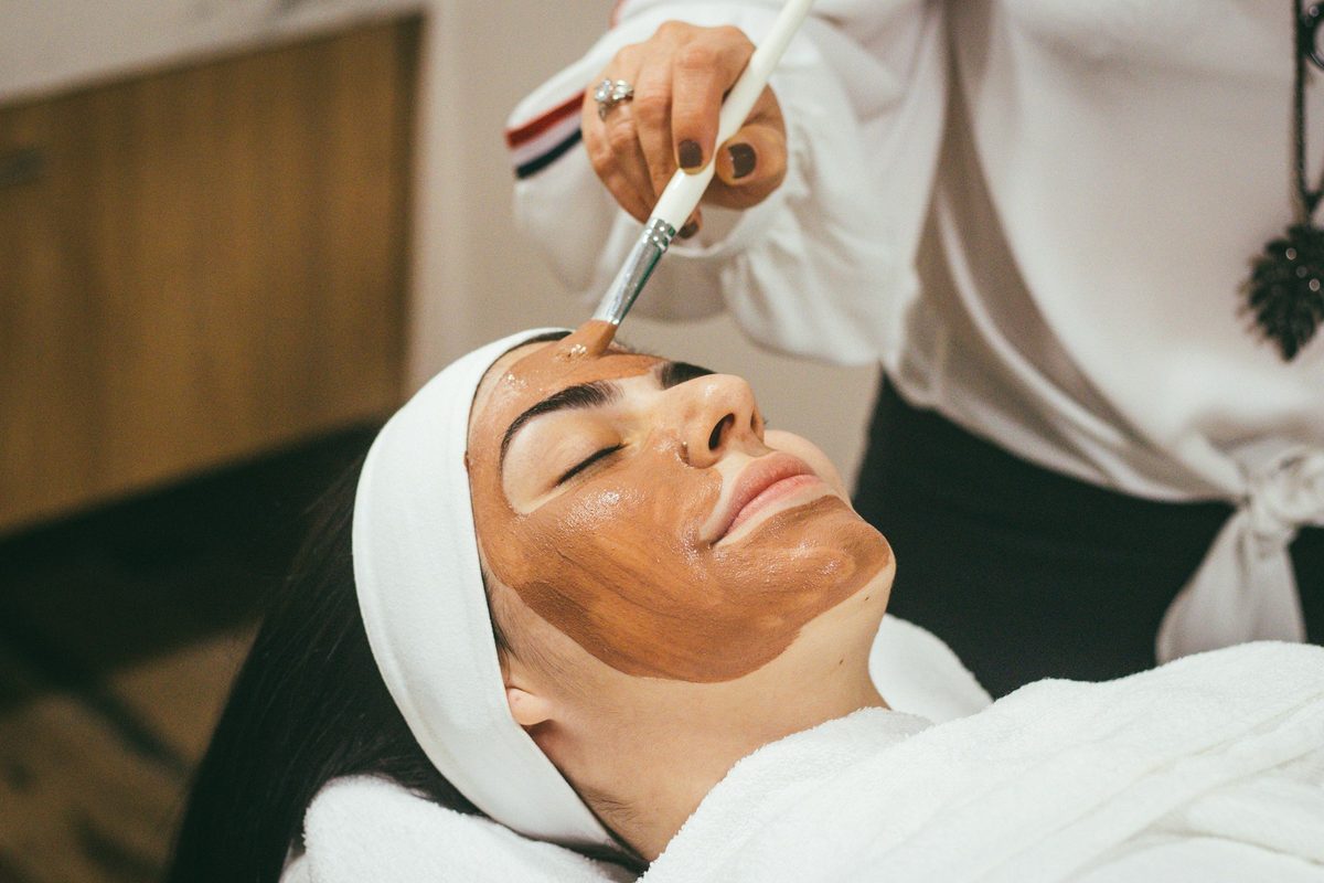 A clinician applying a facial treatment to a reclining client at a med spa