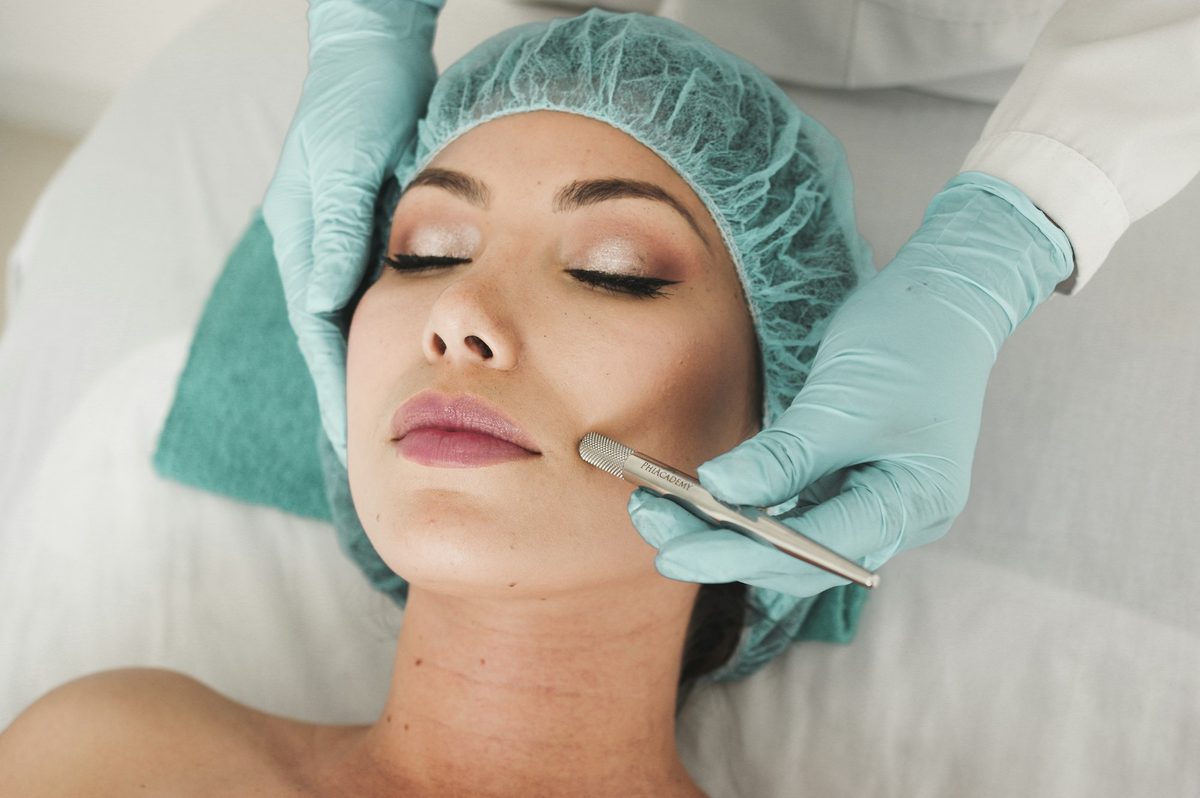 A clinician performing a facial treatment with gloved hands